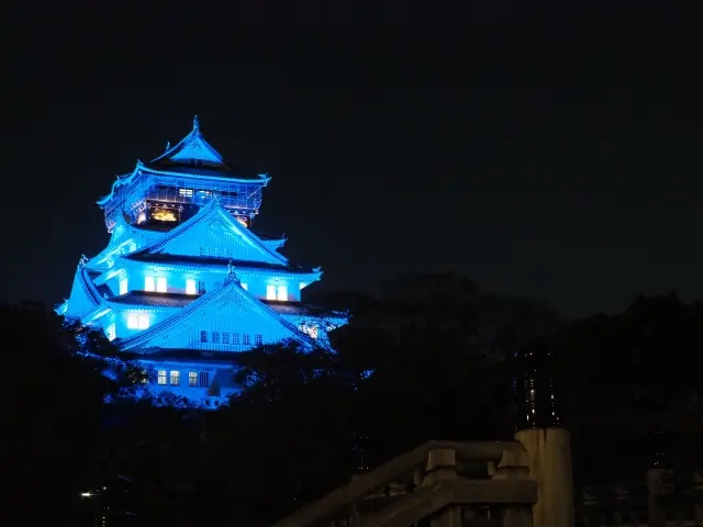 Osaka Castle illuminated in blue at night.